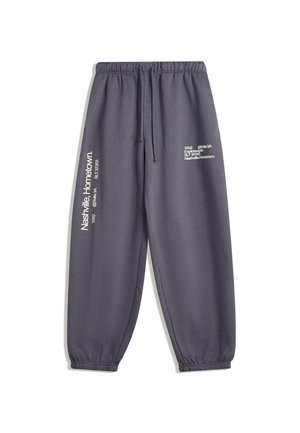 Gray sweatpants with an elastic waistband and cuffs, featuring printed text on the left leg in contrasting white, conveying a modern design.