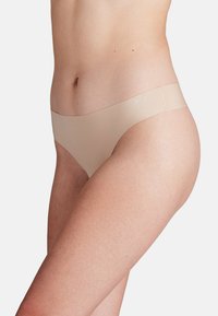Beige stringondergoed met een gladde textuur, voorzien van een brede, naadloze tailleband en een minimalistisch ontwerp, dat een slanke silhouet toont.