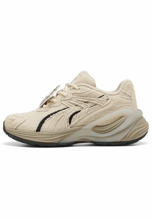 Beige strikket sneaker med tekstureret stof, sort sidestribe, tyk formet sål og snørelukning.