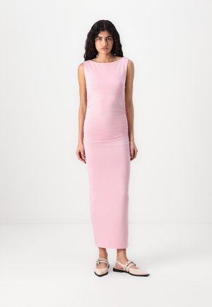 Rosa langermet maxikjole med samlet tekstur, tettsittende silhuett og siderykking, kombinert med lyse slip-on-sko.