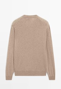 Beige stickad tröja, slät textur, långa ärmar, rund halsringning och ribbade muddar och fåll. Enkel design med enfärgat mönster.