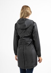 Jachetă neagră impermeabilă cu glugă, manșete elastice și talie cu șnur. Textură netedă, design de lungime medie cu detalii subtile de coasere.