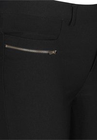 Zwarte broek van een zachte, rekbare stof met een ritszak aan de zijkant. Het ontwerp bevat klassieke stikdetails.