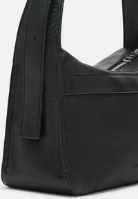 Bolso de mano de cuero negro con una silueta estructurada, correa plana y cierre de cremallera. Destaca por su textura suave y diseño minimalista.