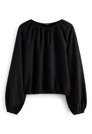 Blouse noire à manches longues avec poignets et ourlet élastiques, présentant un motif floral ajouré subtil et un col rond.