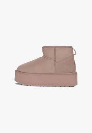 Beżowe zamszowe botki za kostkę z grubą platformą, dekoracyjnym przeszyciem i uchwytem z tyłu, przedstawione od wewnętrznej strony.