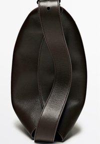 Hnědá kožená kabelka oválného tvaru s prohnutým popruhem. Textura je hladká, s jemným prošitím podél okrajů.