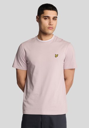 T-shirt a maniche corte di colore rosa chiaro in tessuto di cotone, con colletto rotondo e un piccolo logo di un uccellino giallo sul lato sinistro del petto.