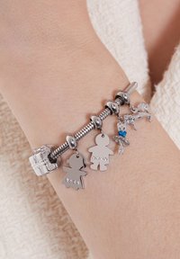 Zilveren charmearmband met kind- en ballerina-charms, uitgerust met cubic zirconia-accenten op een flexibele metalen band en een veilige sluiting.