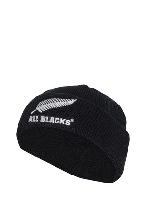 Bonnet tricoté noir avec texture côtelée, arborant une fougère brodée blanche et le logo "ALL BLACKS" à l'avant. Design simple et ajusté.
