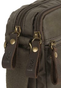 Bolsa de lona marrón con cremalleras dobles y herrajes dorados, tiradores de cremallera de cuero y una superficie texturizada. Diseño rectangular compacto.