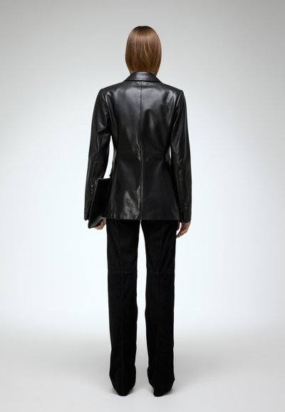 Black leather blazer with a fitted silhouette, single-button closure, and sleek lapels, paired with black suede pants featuring seam details.