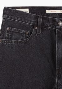 Zwarte baggy vaderjeans van denim met een soepele textuur, met een klassieke vijf-pocket ontwerp en zichtbare stikseldetails.