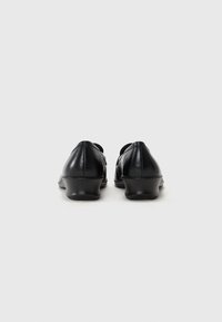 Black leather shoes with a low heel, rounded toe, and smooth texture. Features a simple design with no visible hardware or patterns.