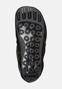 Suola di scarpa nera con una superficie in gomma texturizzata, caratterizzata da motivi circolari per la presa e un logo in rilievo. Il design sottolinea la trazione e la flessibilità.