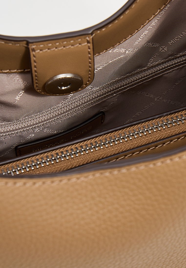 Tan läderhandväska med en slät textur, med ett metalliskt tryckknappslås. Inuti finns en dragkedjeficka och märkesinredning.