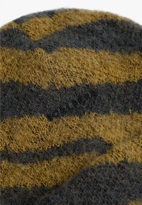 Gorro de lana a rayas con tonos gris oscuro y mostaza, que presenta una superficie suave y texturizada, con un sutil logotipo tejido en la tela.