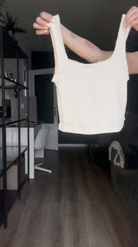 Cremfarbener Crop-Top mit breiten Trägern und strukturierten Kanten, aus weichem Stoff gefertigt, mit einer taillierten Silhouette und einer glatten Oberfläche.