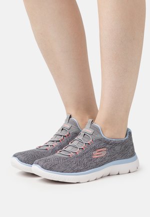 Grijze sportschoenen met een gestructureerde gebreide bovenkant, roze accenten en een witte zool; voorzien van elastische veters en een ondersteunend ontwerp.