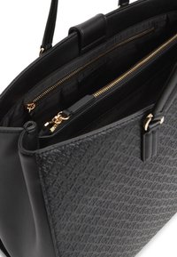 Μαύρη υφασμάτινη τσάντα ώμου με διπλές λαβές, με χρυσά φερμουάρ στις τσέπες και επένδυση από υφασμάτινη φόδρα με λογότυπο στο εσωτερικό.