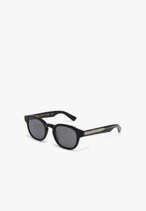 Lunettes de soleil rectangulaires noires avec verres foncés et touches décoratives argentées sur les branches, présentées sur un fond blanc.