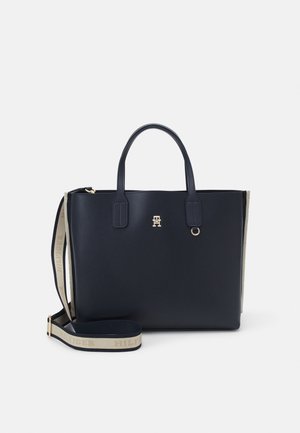 Borsa a mano blu navy in materiale sintetico liscio, con doppio manico superiore, tracolla regolabile, dettagli in oro e logo in evidenza sul davanti.