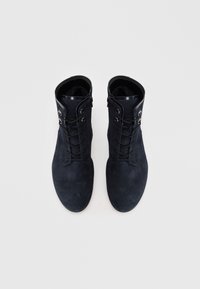 Bottines en daim noir à bout arrondi, présentant un design à lacets, des œillets en métal argenté et un bord en cuir laqué au col.