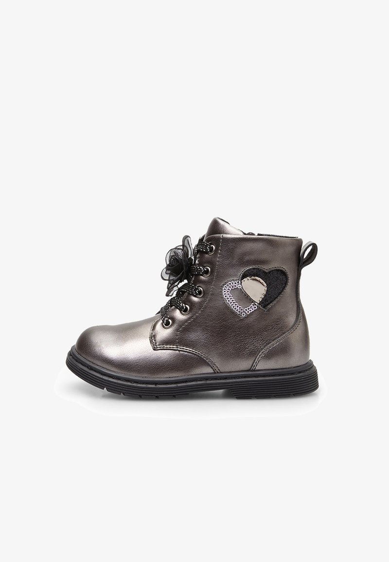 Botas metálicas grises hasta el tobillo con herrajes negros, que presentan un detalle en forma de corazón y un acento de cordones. Punta redonda y suela de goma plana para mayor estabilidad.