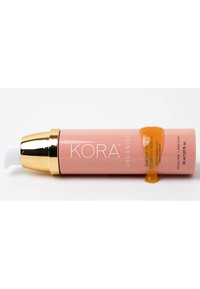 Sérum de vitamine C à la prune Kakadu de Kora Organics dans un flacon cylindrique rose doux avec des accents en or ; le sérum s'écoule de la pompe ; 30 ml.