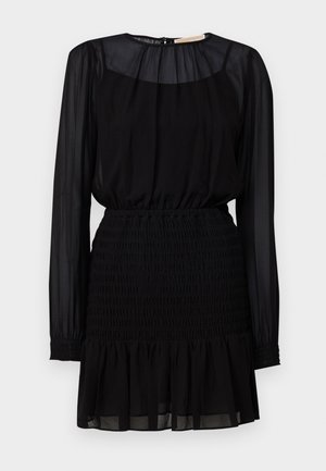 Mustapuku, jossa on pitkät läpinäkyvät hihat, smockattua vyötäröä ja kerroksellinen röyhelöhelma. Valmistettu kevyestä, virtaavasta kankaasta.