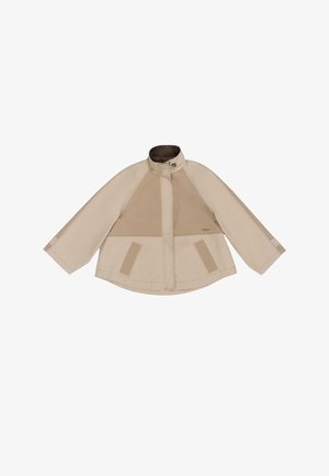 Beige jakk, millel on kõrge krae, ribakujuline tekstuur rinnal ja küljetaskud. Omab lõdva varrukatega ja minimalistlikku kujundust.