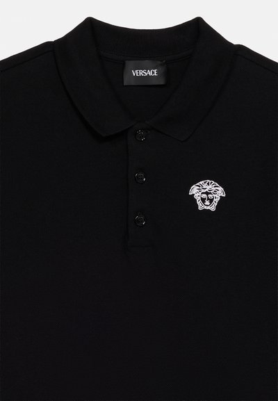 Μαύρο πόλο πουκάμισο Versace με τρία μαύρα κουμπιά, γιακά και λευκό κεντημένο λογότυπο κεφαλής Μέδουσας στην αριστερή πλευρά του στήθους.