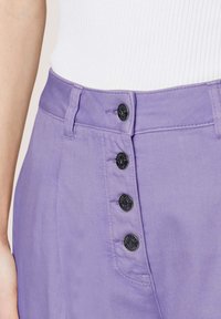 Paarse high-waisted broek met vijf zwarte knopen en subtiele diagonale textuur. Beschikt over een soepele tailleband en zijzakken.