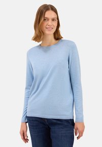 Hellblaues Langarmpullover aus weichem Strickmaterial, mit einem runden Ausschnitt und gerippten Bündchen, kombiniert mit dunkelblauen Jeans.
