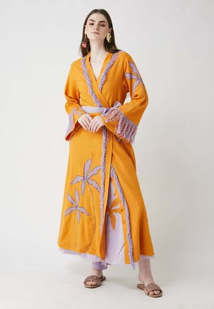 Kimono largo naranja con bordados de lavanda, con flecos en las mangas y bordes, y un cinturón atado en la cintura.