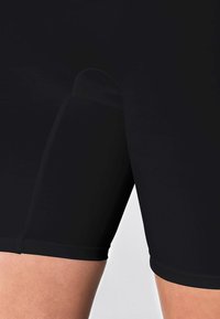 Pantaloni sportivi neri realizzati in un tessuto liscio ed elastico, con lunghezza a metà coscia e design aderente, senza motivi o dettagli visibili.