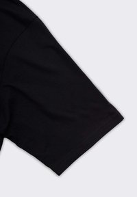 T-shirt nero a maniche corte in tessuto con cuciture visibili vicino all'orlo delle maniche, su uno sfondo chiaro e neutro.