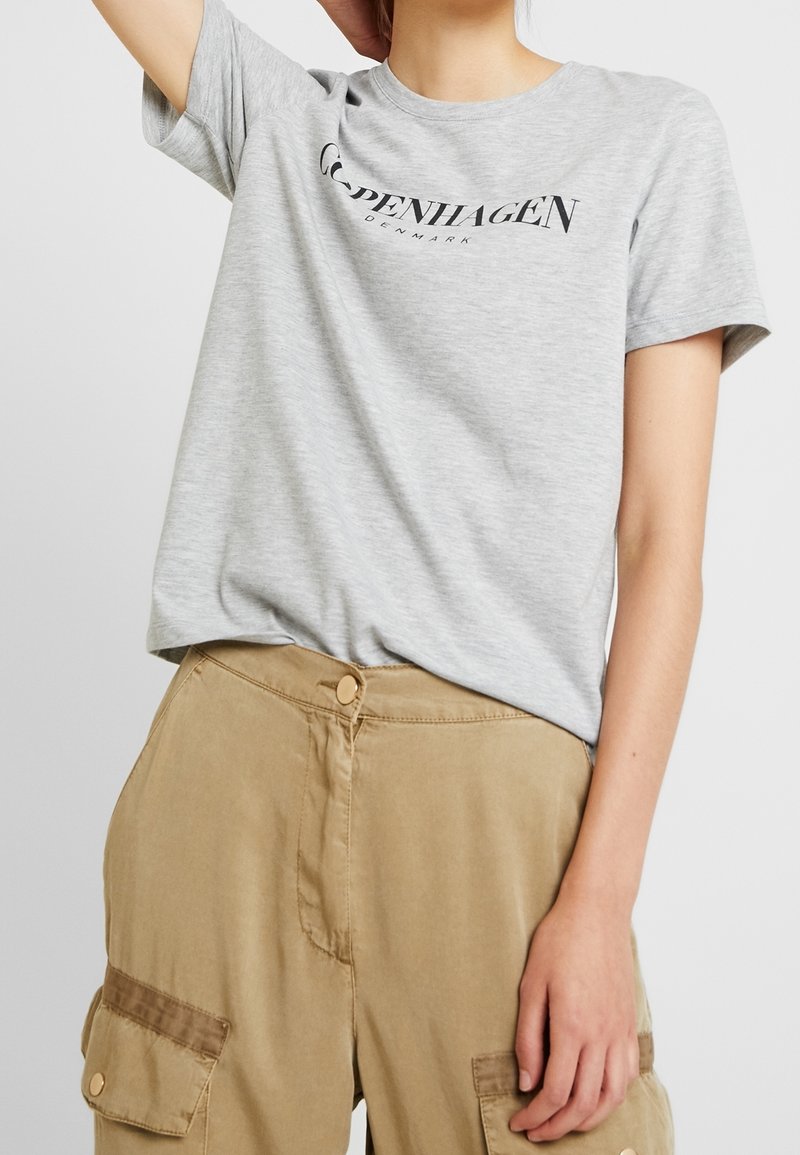 Grå bomulds t-shirt med et sort "København Danmark" logo, rund halsudskæring og afslappet pasform, parret med beige cargo bukser med lommer.