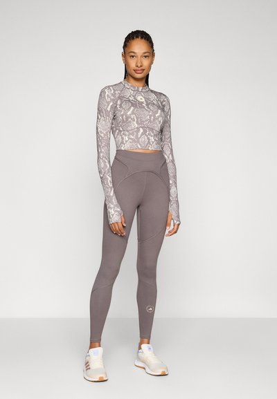 Langermet, tettsittende crop topp med slangeprintmønster, kombinert med høytlivs grå leggings med teksturerte paneler og detaljer.