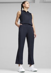 Námornícky bezrukávový polo top s golierom a zapínaním na gombíky, kombinovaný s prispôsobenými námorníckymi nohavicami a bielou športovou obuvou.