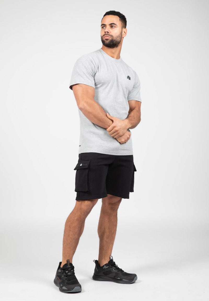 Gray cotton t-shirt with short sleeves and a black logo, paired with black cargo shorts featuring dual side pockets and black athletic shoes.
