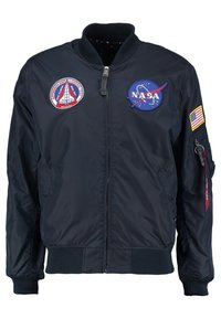 Blouson aviateur bleu marine avec fermeture éclair avant, écussons NASA et navette spatiale sur la poitrine, et un écusson du drapeau américain sur la manche droite.