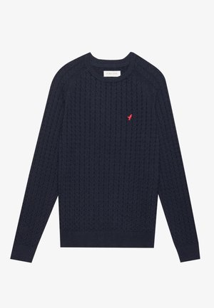 Maglione a trecce blu navy con maniche lunghe, polsini e orlo a coste. Presenta un piccolo logo rosso sulla parte sinistra del petto.