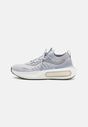Light gray athletic shoe with a breathable knitted upper, cushioned white sole, and subtle accents. Features laces and a seamless design.