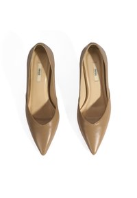 Des escarpins à bout pointu en cuir nude avec une texture lisse et une silhouette épurée. Les semelles intérieures sont de couleur beige, avec un logo à l'intérieur.