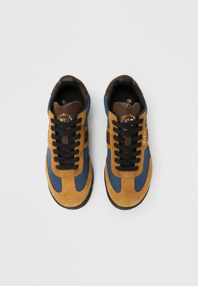 Sporta apavi ar brūnās zamšādas virsu un ziliem tekstila akcentiem, melnām šņorēm un brūnu ādas papēdi. Plakana gumijas zole.