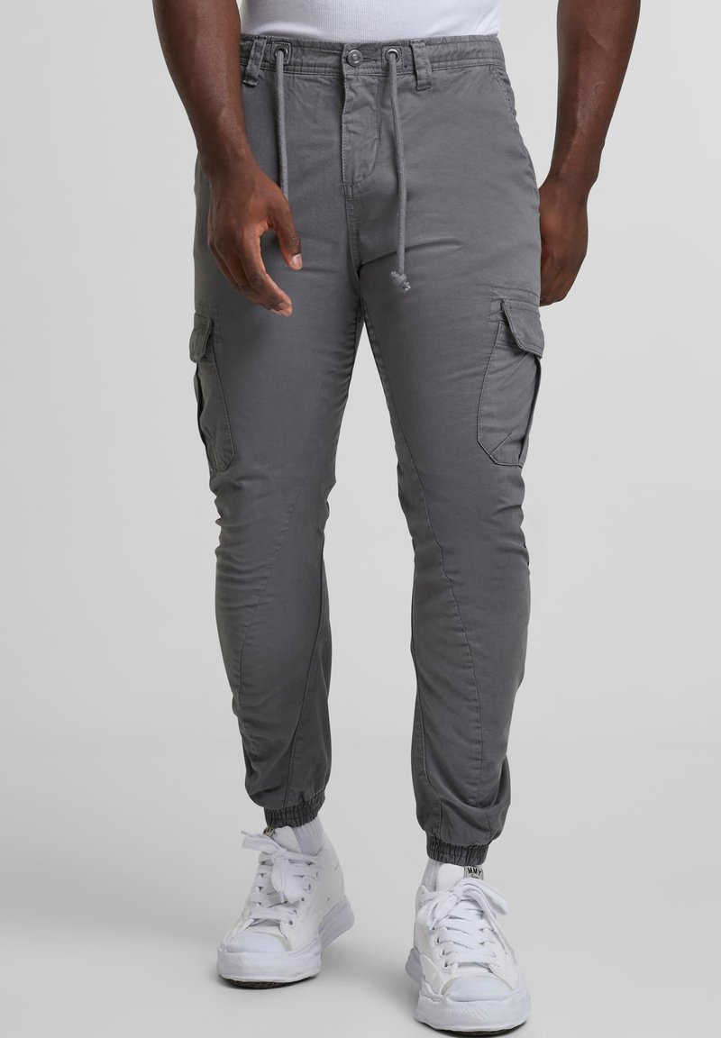 Joggers de cargo grises con pierna tapered, puños elásticos, cintura con cordón y bolsillos laterales. Hechos de una tela ligera y suave.