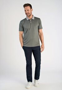 Harmaa polo-paita, jossa on vaaleanharmaa kaulus, yhdistetty tummansinisiin housuihin. Siistit linjat, lyhyet hihat ja minimaalinen yksityiskohtaisuus.