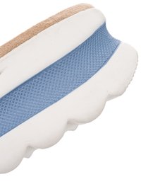 Close-up van de zool van een sneaker met een witte, dikke loopzool, een blauwe, getextureerde middenzoolstrip en een beige suède bovenrand.