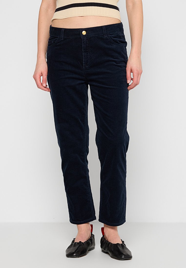 MarineblaueCorduroyhose mit geradem Schnitt, ausgestattet mit einem Knopfverschluss vorne und Seitentaschen, kombiniert mit schwarzen Ballerinas mit roten Akzenten.